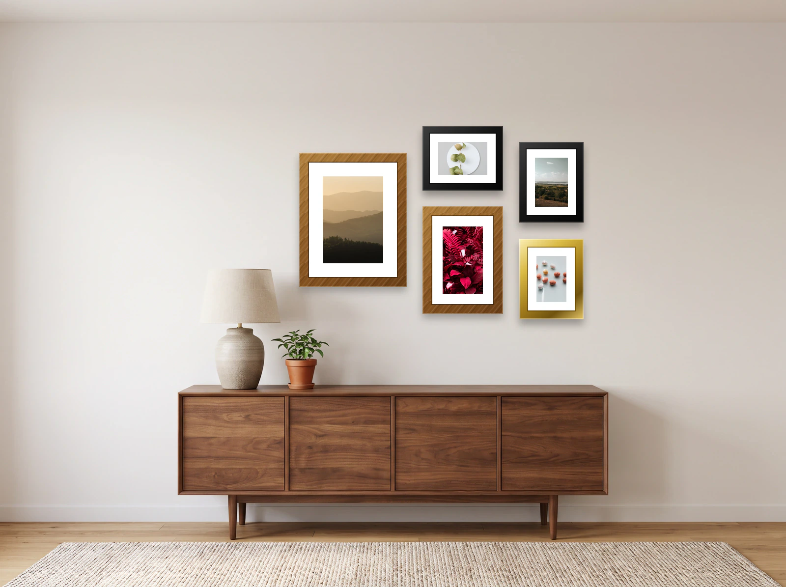 Mixed family gallery wall template: five wood, black and gold frames of different sizes above a walnut sideboard, beside a table lamp